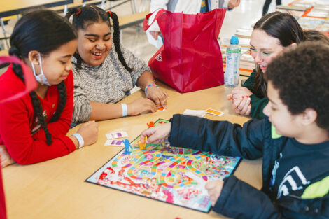 Lafayette student sits with elementary students playing a board game