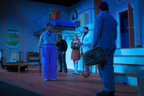 students in a stage production act on stage with blue dramatic lighting