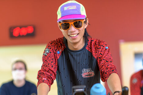 student rides a spin bike wearing a cycling cap and sunglasses
