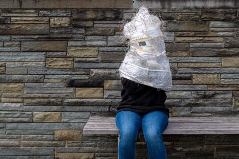 Student sits with plastic shape over her head