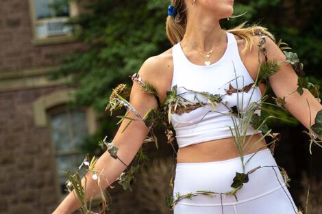 Student wears white with leaves and vines ascending her body