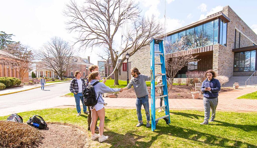 Remy Oktay and other students with a ladder on the Quad near Skillman