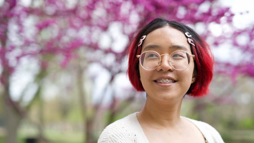 Shirley Liu smiles, cherry blossoms in background