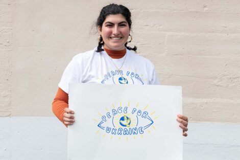 Student holds a poster and wears a shirt
