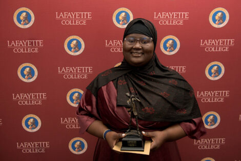 Fatimata Cham '23 stands against a Lafayette College backdrop holding an award