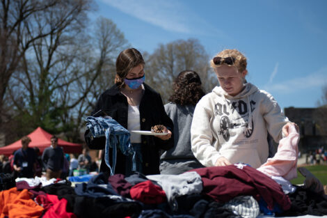 students look through piles of clothing offered as part of a pop-up thrift shop on the Quad