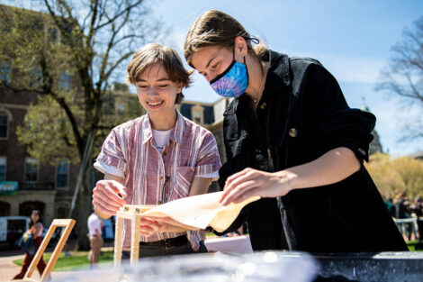 two students work on a paper-making project on the Quad