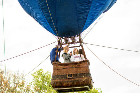 students in a hot air balloon basket are airborne