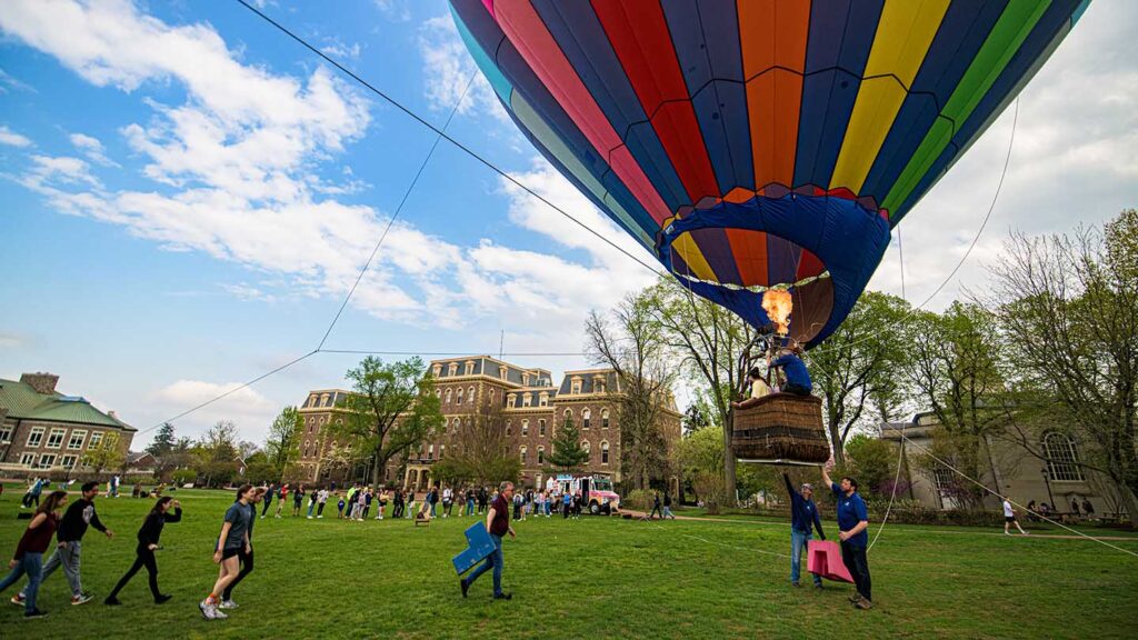 students gather on the Quad where the hot air balloon sits with a basket