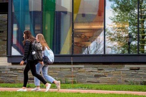 students walk by Skillman library, the reflection shows a colorful hot air balloon