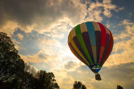 sunlight shines through clouds as a hot air balloon floats in the air