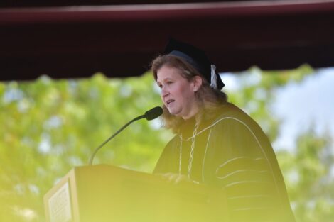 President Nicole Hurd in cap and gown speaks at podium