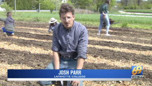 Josh Parr kneels in rows of dirt in a flower bed, his name is across the bottom of the screen