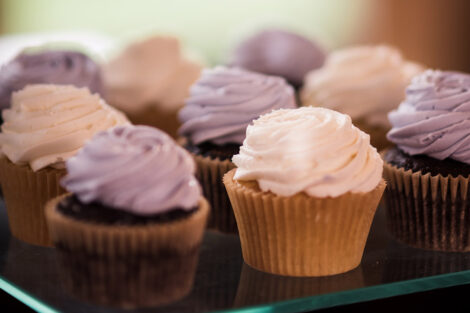 a plate full of cupcakes with white and lavender icing