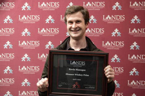 student holds a Landis award in front of a Landis backdrop