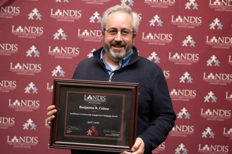 Prof. Ben Cohen holds an award in front of a Landis backdrop