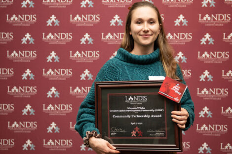 Miranda Wilcha holds a Landis award in front of a Landis backdrop