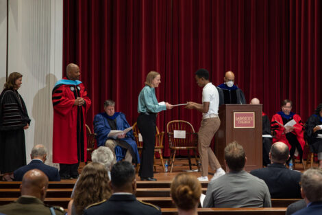 faculty member hands a student a certificate on stage in Colton Chapel