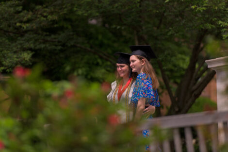 Two graduates smile in cap.