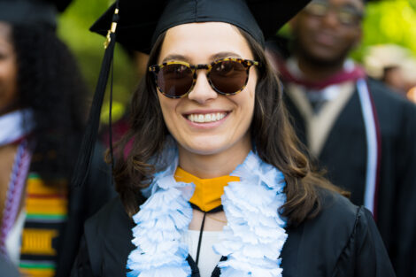 A graduate wearing sunglasses smiles