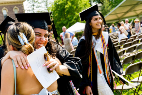 A graduate smiles while hugging someone.