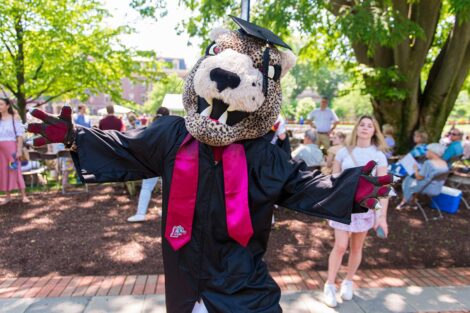 leopard mascot wears cap and gown and extends arms