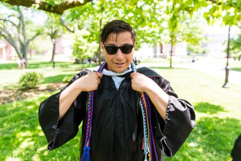 student in sunglasses and gown adjusts his honor cords