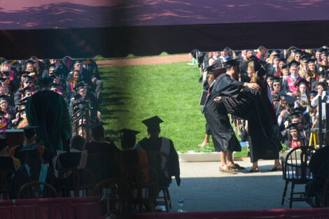 Nicole Farmer Hurd hugs a student on the commencement stage
