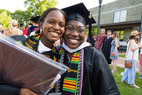 two graduates smile