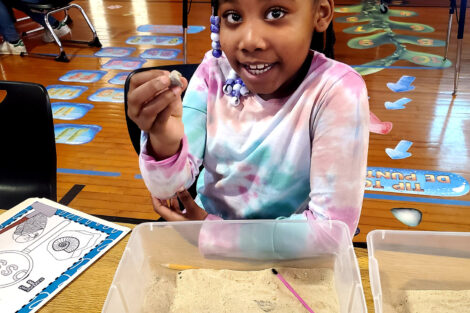 A first grader from Paxinosa holds up a fossil she found during a Connected Classrooms paleontology lesson.