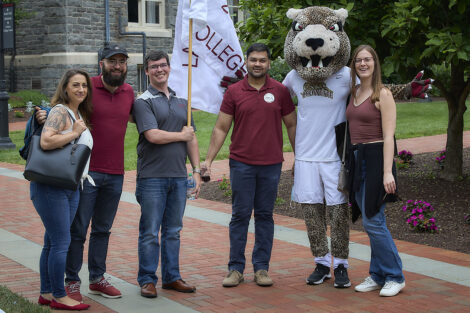 Alumni smile with the Leopard; one holds a Lafayette College flag.