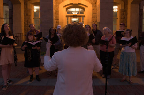 Choir sings in front of Pardee Hall at night.