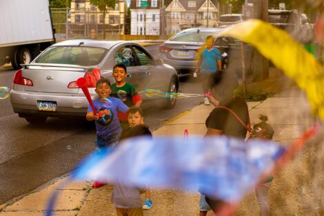 young children run on a sidewalk outside the West Ward Sale