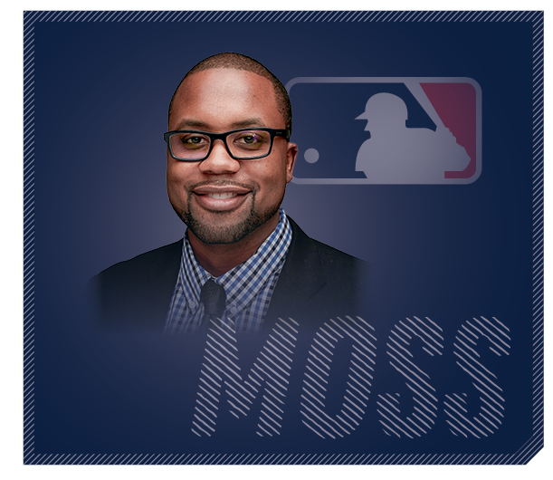 Kevin Moss smiles, Major League Baseball logo set-off behind him