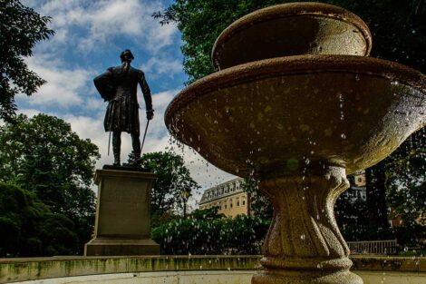 water splashes as it pours down the fountain at Colton Chapel, a statue of Marquis de Lafayette is behind