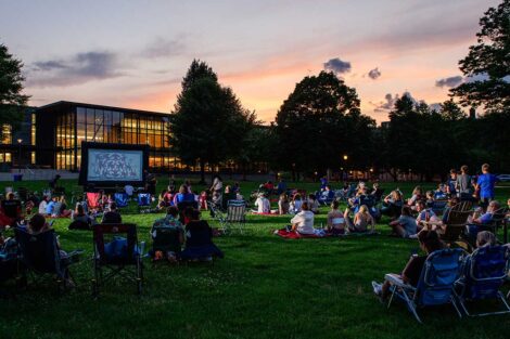 Easton community members sitting on the lawn of the Quad watching a free outdoor movie screening with Skillman Library in the background