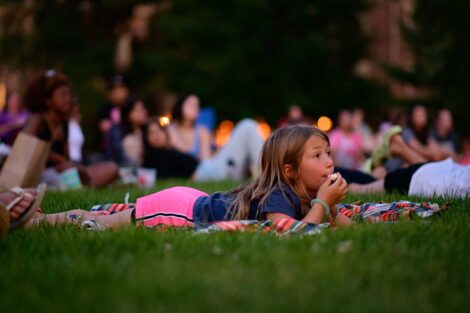 Young girl laying on the lawn of the Quad watching a free outdoor movie screening