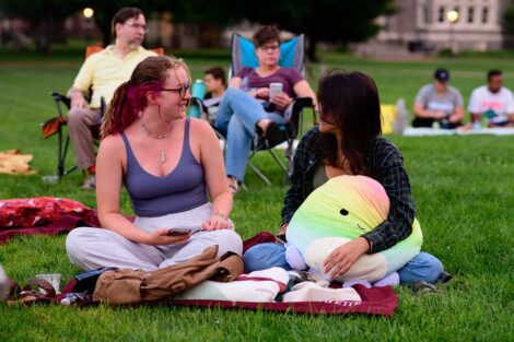 Two Lafayette students sitting on the lawn of the Quad talking and awaiting the free outdoor movie screening