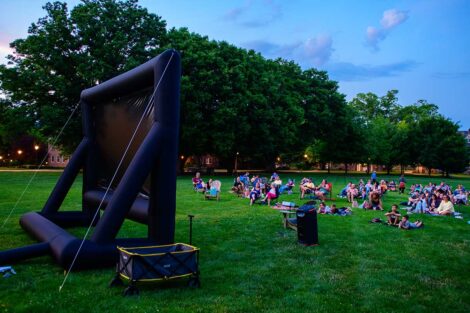 Blow-up movie screen on the Quad with Easton and Lafayette community members sitting on the lawn watching a free outdoor movie screening