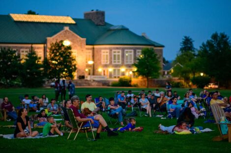 Easton community members sitting on the lawn of the Quad watching a free outdoor movie screening with Farinon in the background