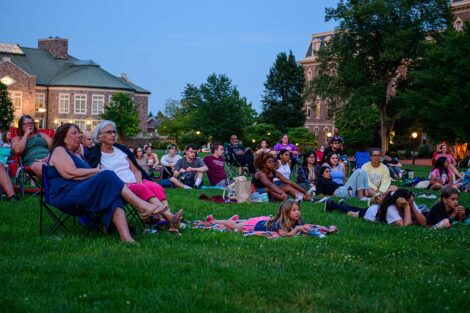 Easton community members sitting on the lawn of the Quad watching a free outdoor movie screening