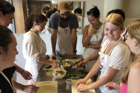 Students on the Summer 2022 Study Abroad Italy trip learn how to make pasta, gathered around a kitchen table