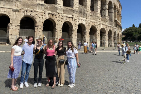 A group of students pose in front of the Colosseum during the Italy 2022 Study Abroad trip