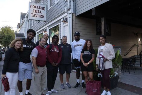 Lafayette College President Nicole Hurd, head football coach John Troxell, football team members, and Leopards mascot standing in front of College Hill Tavern