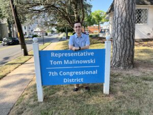 Dylan Gooding leans on the sign for congressional rep