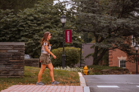 A student walks across a street on Lafayette College's campus.