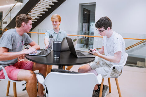 Students with laptops sit at a table in Rockwell Integrated Sciences Center.