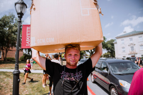 A student carries a box over their head.