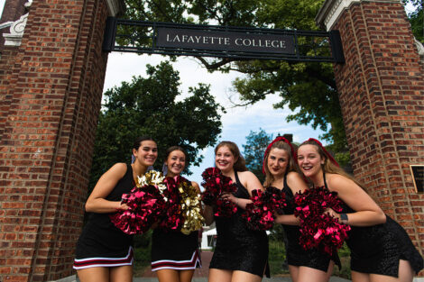 Cheerleaders with pom poms outside of a Lafayette College sign.