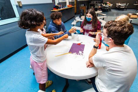 Lafayette students sit at a table and do arts and crafts with young Easton students